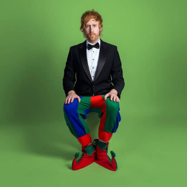 Comedian Mark Simmons dressed in a tuxedo and shirt on his upper body, and jester outfit for the lower half